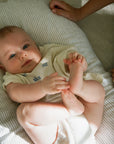 Baby Laying In A Pinstripe Bubba Cloud Baby Lounger. Baby Is Looking At The Camera With Blue Eyes Wearing A White Body Suit.